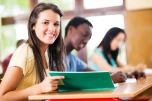 Group of teenage students writing in notebooks.